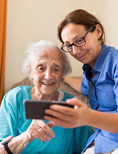 Nurse holding a phone for older woman